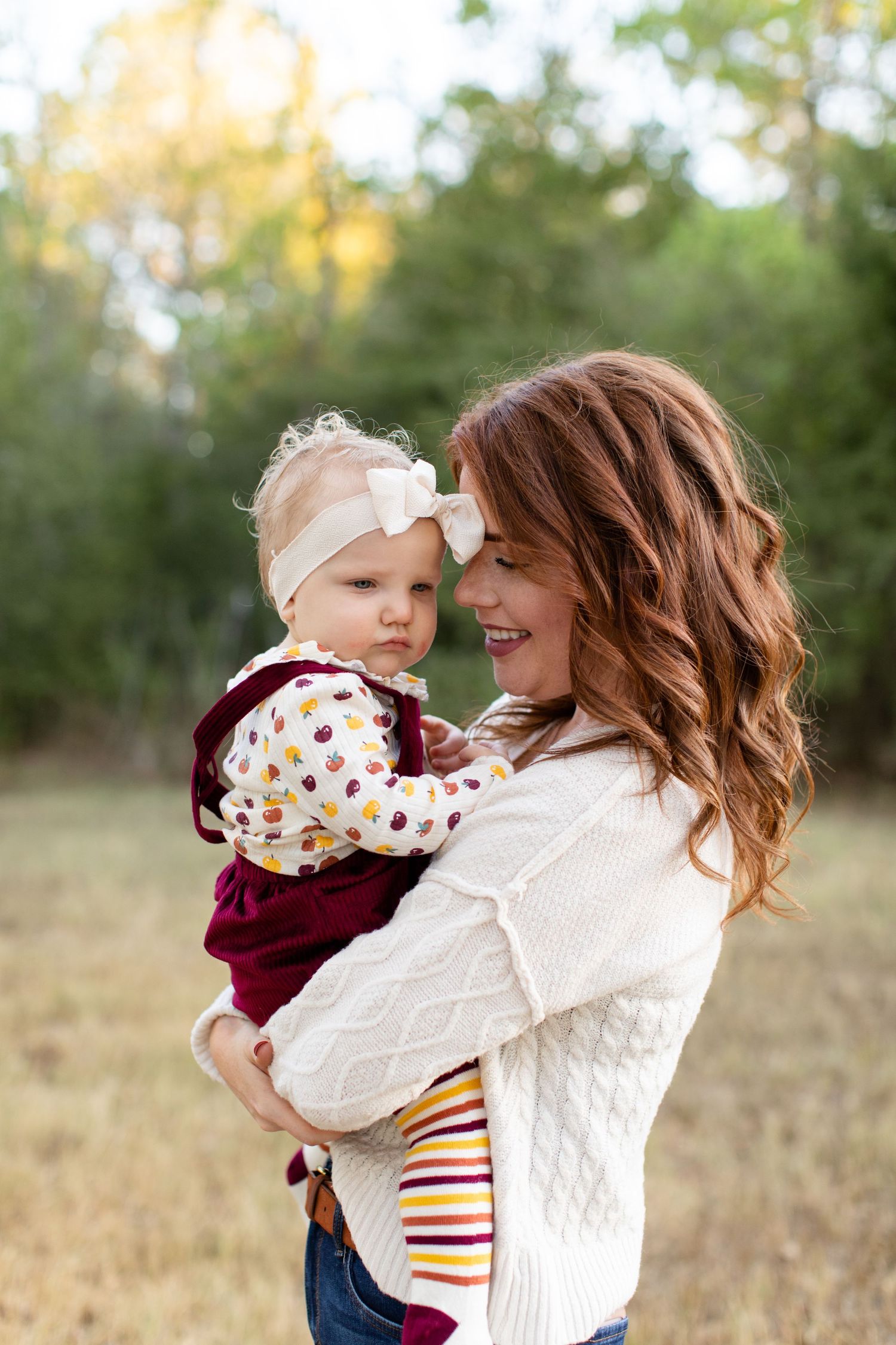 A heartwarming embrace between caregiver and baby in coordinating fall outfits outdoors.