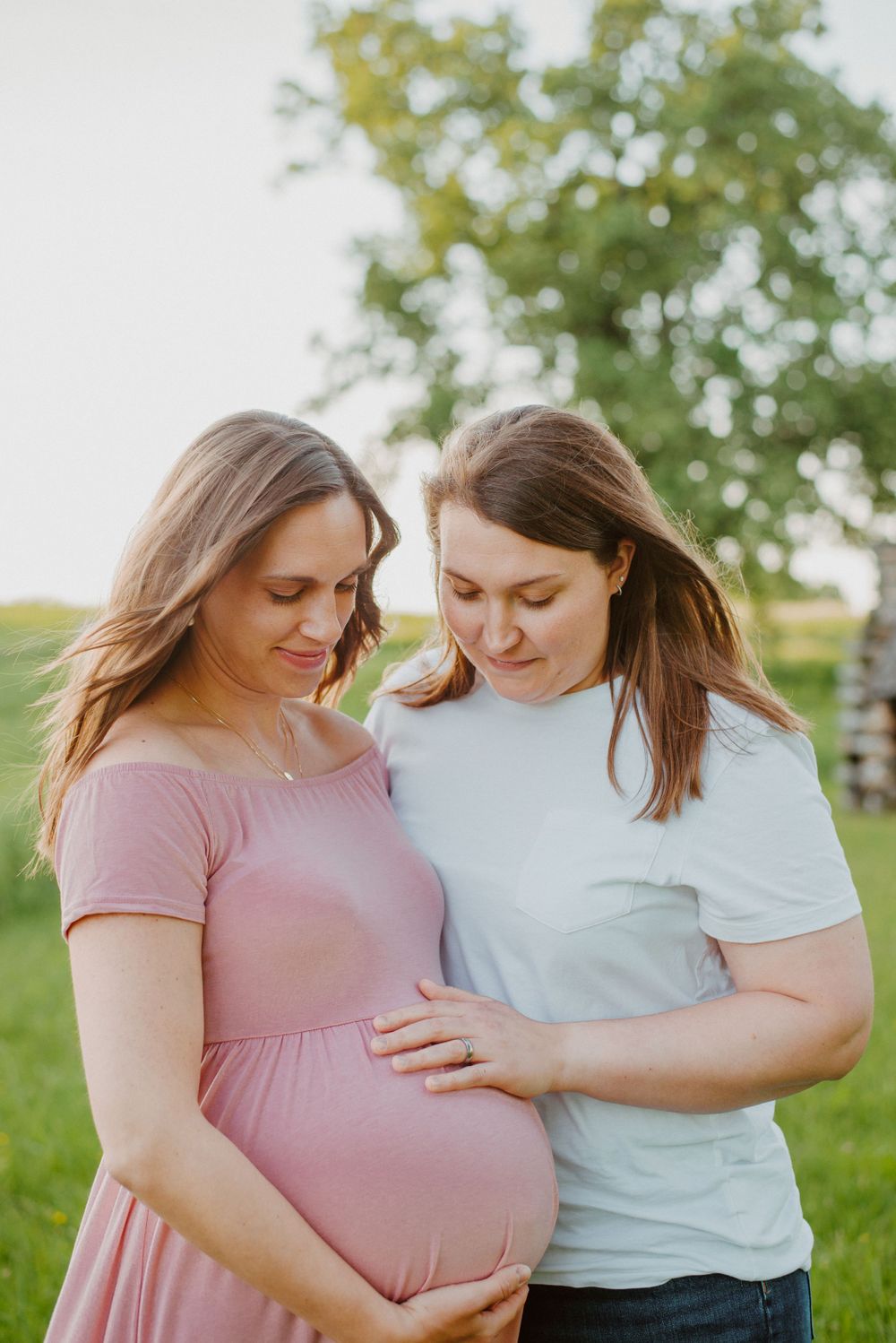 Two moms looking down at baby during maternity session in Valley Forge Park