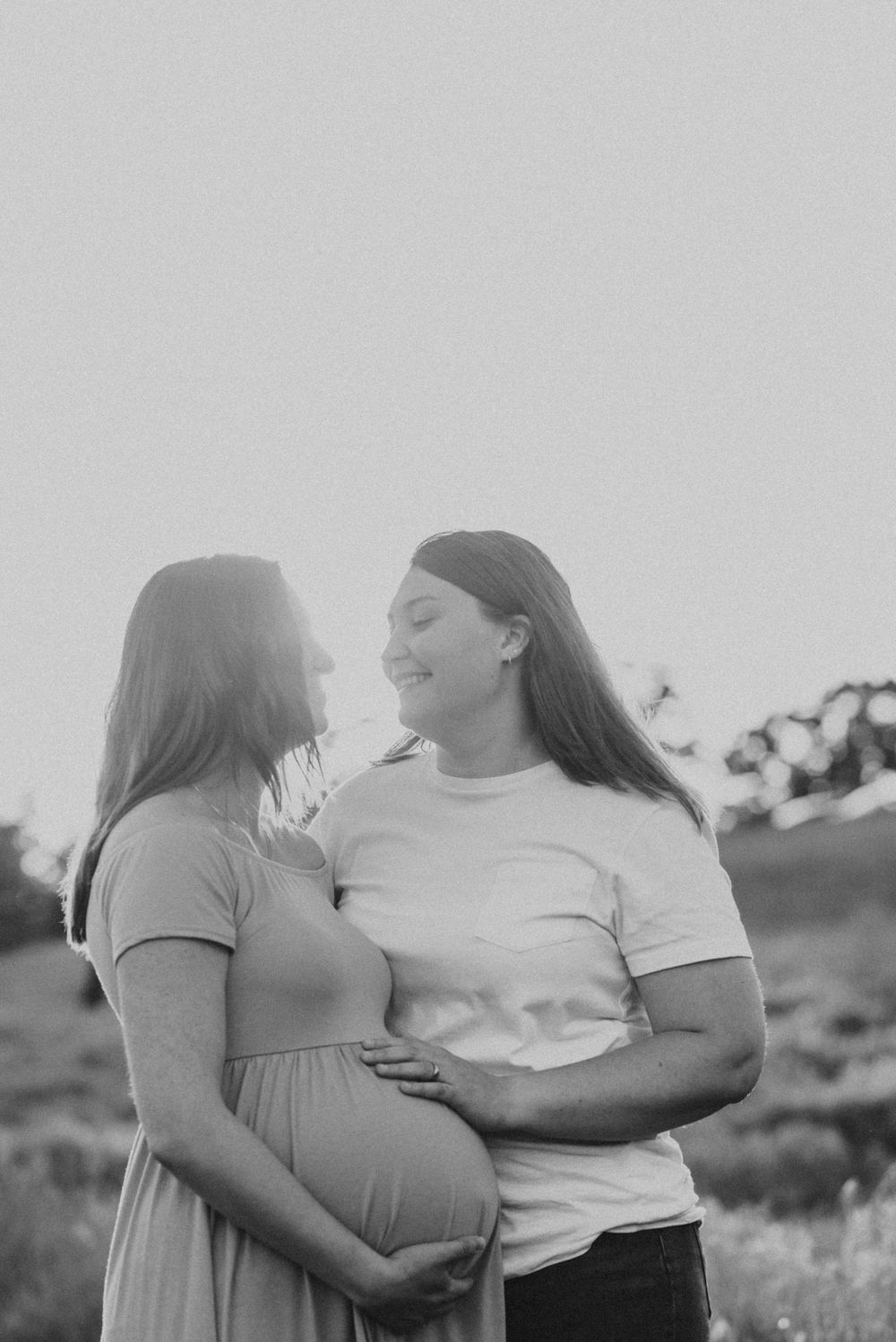Candid moment between two moms during maternity session golden hour