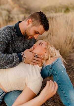 Intimate couple moment captured in golden field with soft afternoon lighting.