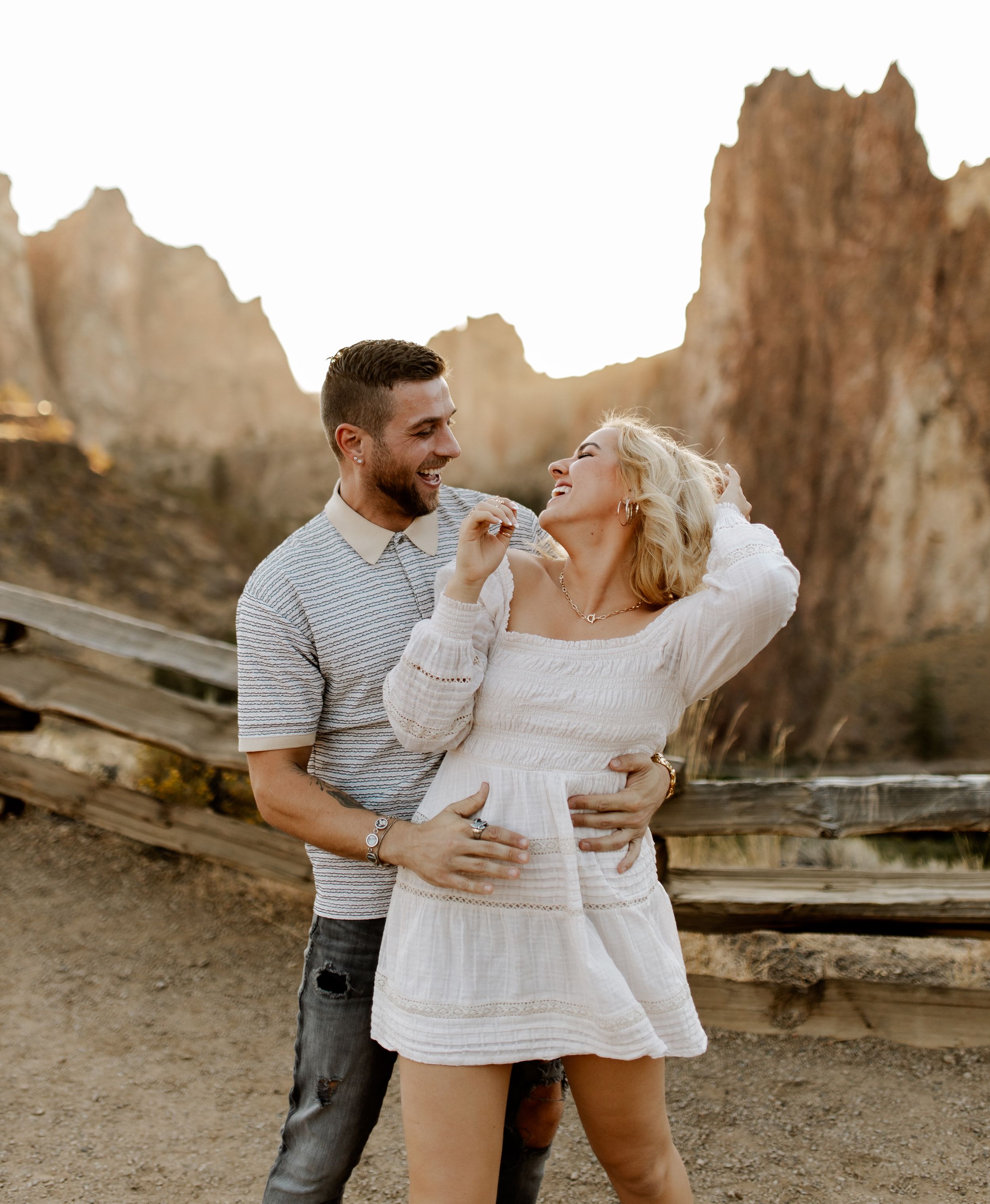 Intimate couple embraces during sunset photoshoot at scenic desert rock formations.