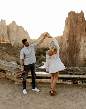 Dancing couple against desert landscape with dramatic rock formations.