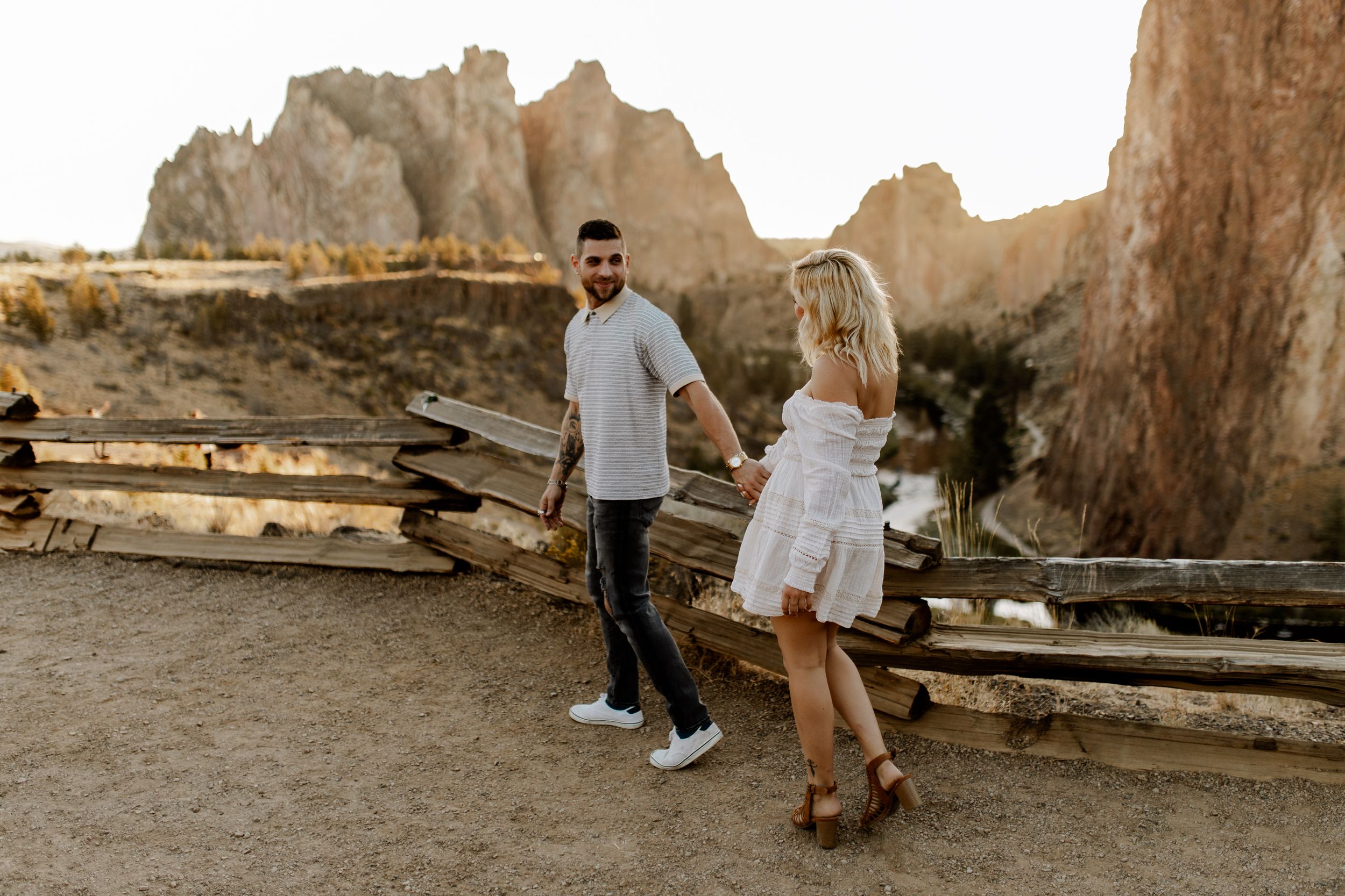 Couple enjoying sunset at scenic desert overlook with rocky cliffs.