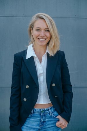 Portraitfotografie: Businessporträt einer Frau im Blazer vor neutralem Hintergrund.