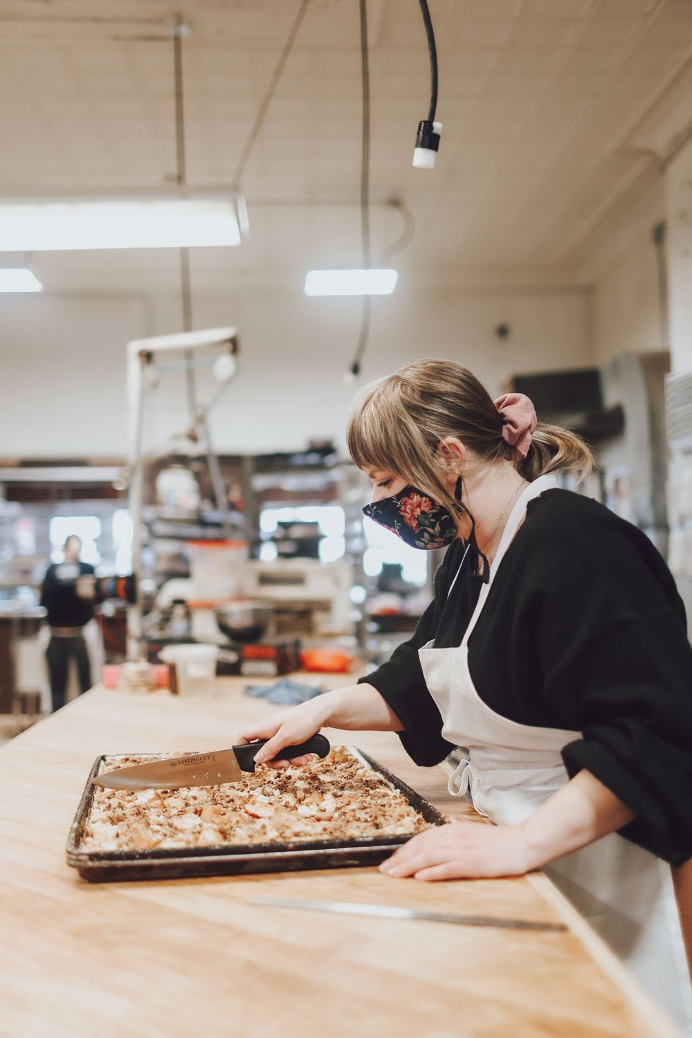 Baker working on preparing food items on large wooden prep table.