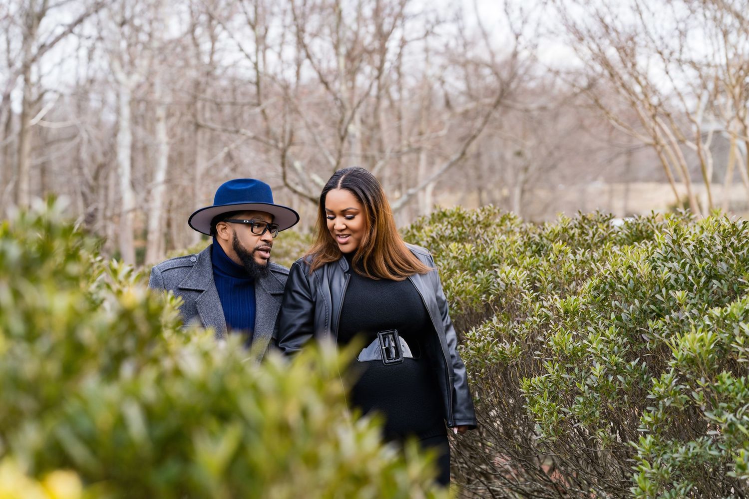 A joyful couple share an intimate moment outdoors while wearing winter coats.
