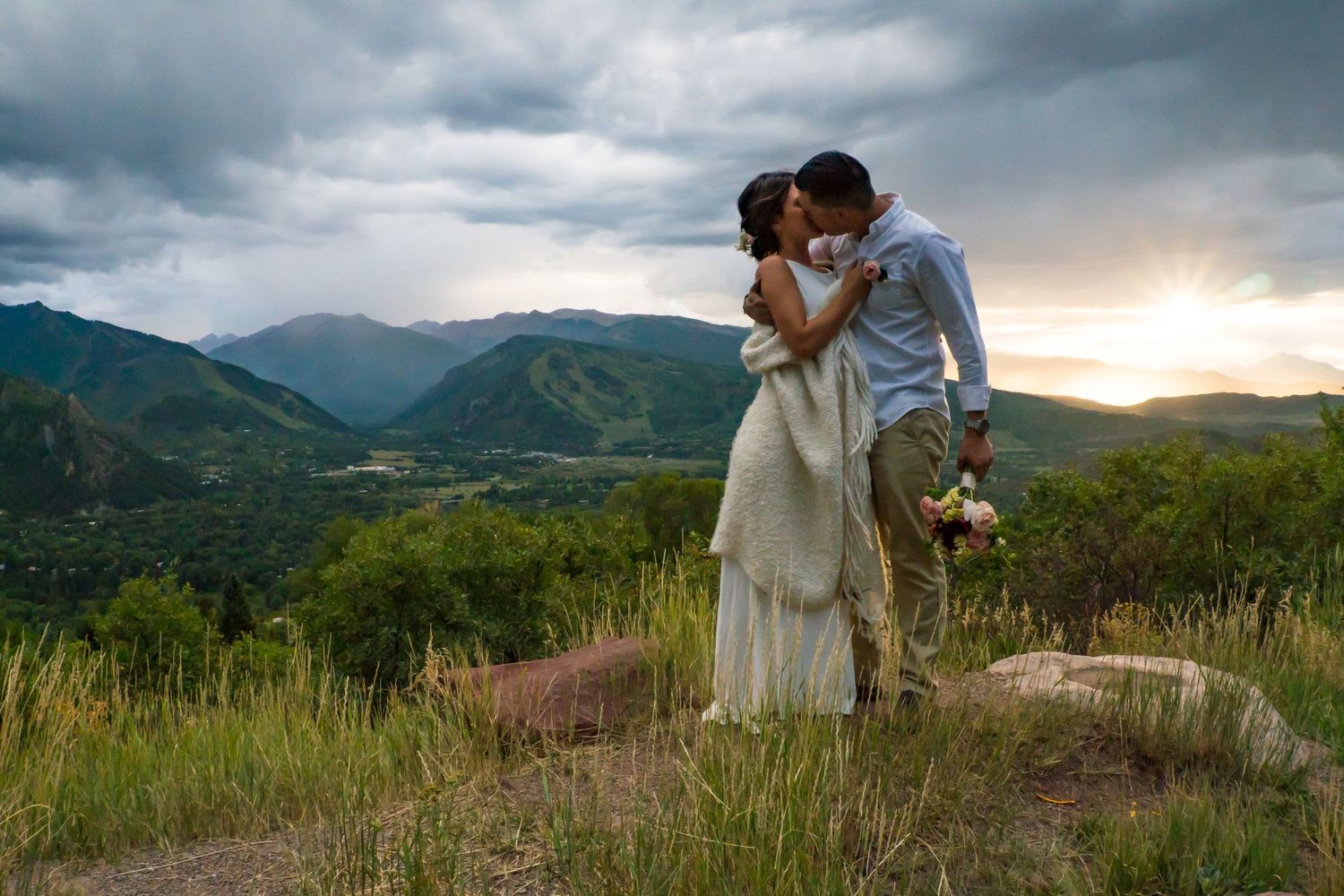 Romantic mountain top scene at sunset with rolling hills and dramatic sky in the background.