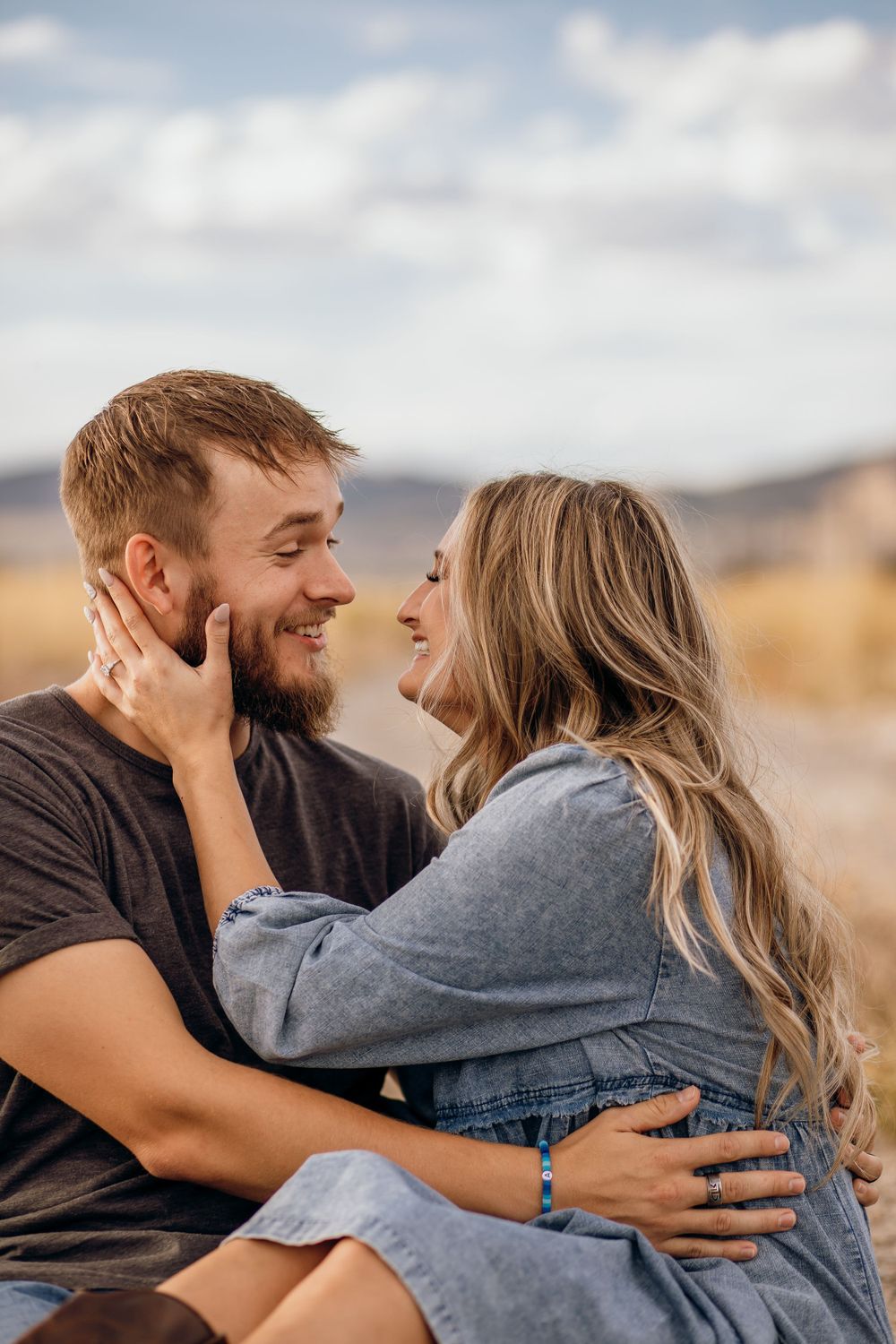 Joyful couple laughing and embracing in golden outdoor setting during sunset.