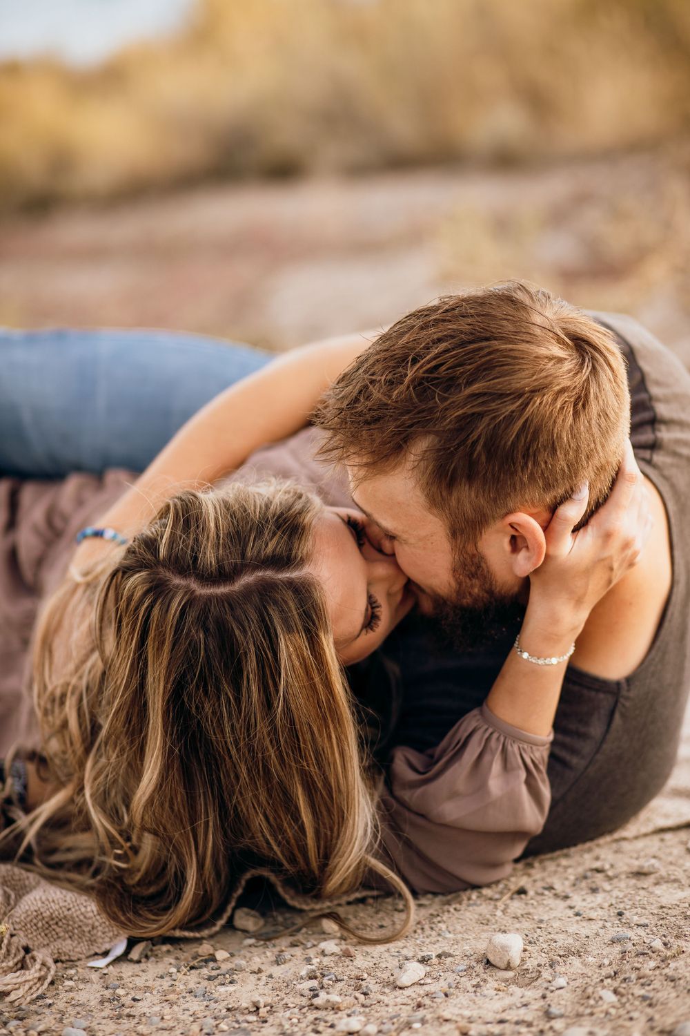 An intimate moment shared outdoors with mountains and desert terrain in the background.