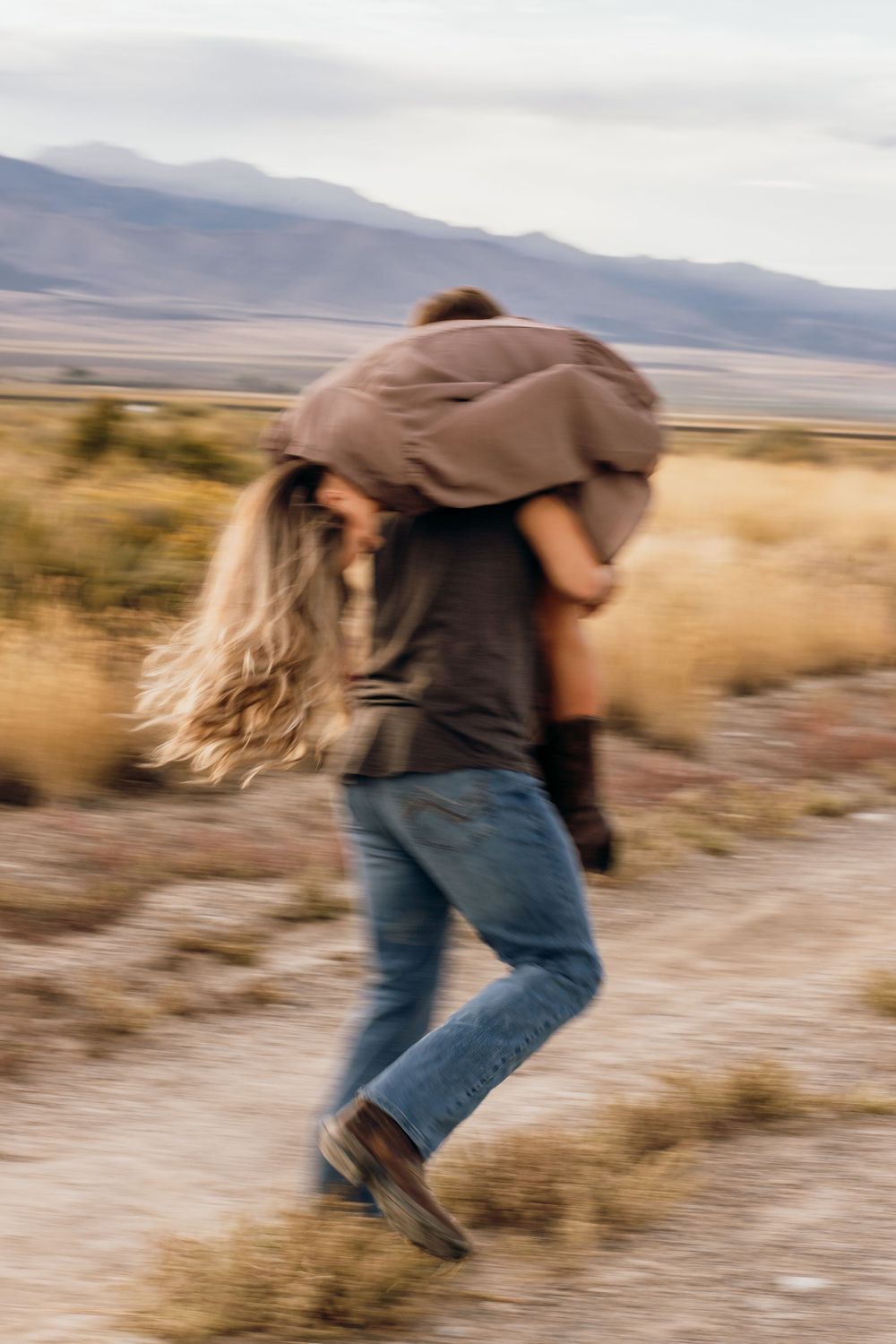 A blurred motion shot of someone being carried through a desert landscape with mountains in the background.