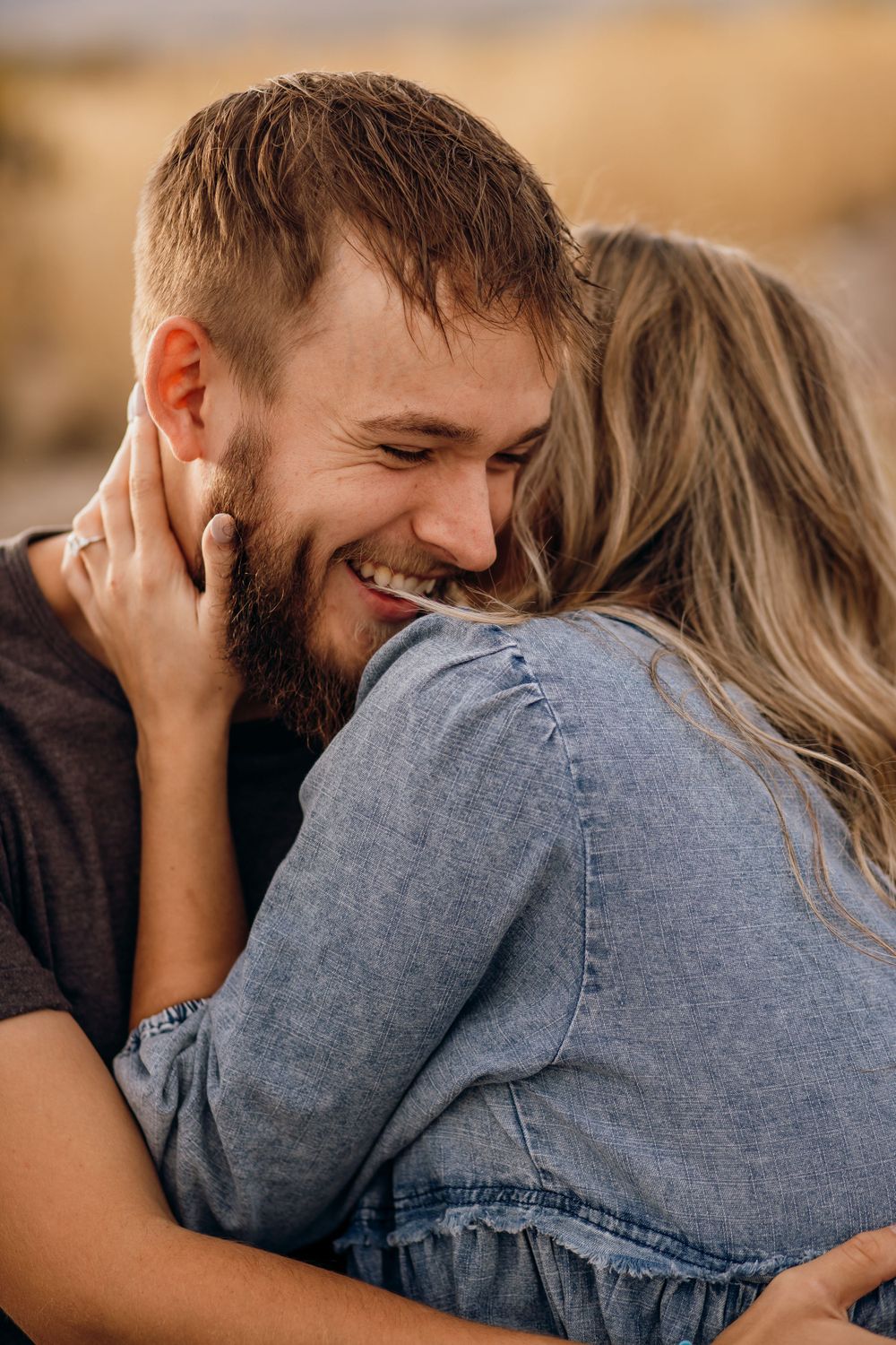 Close-up of couple sharing intimate laughter while embracing outdoors.