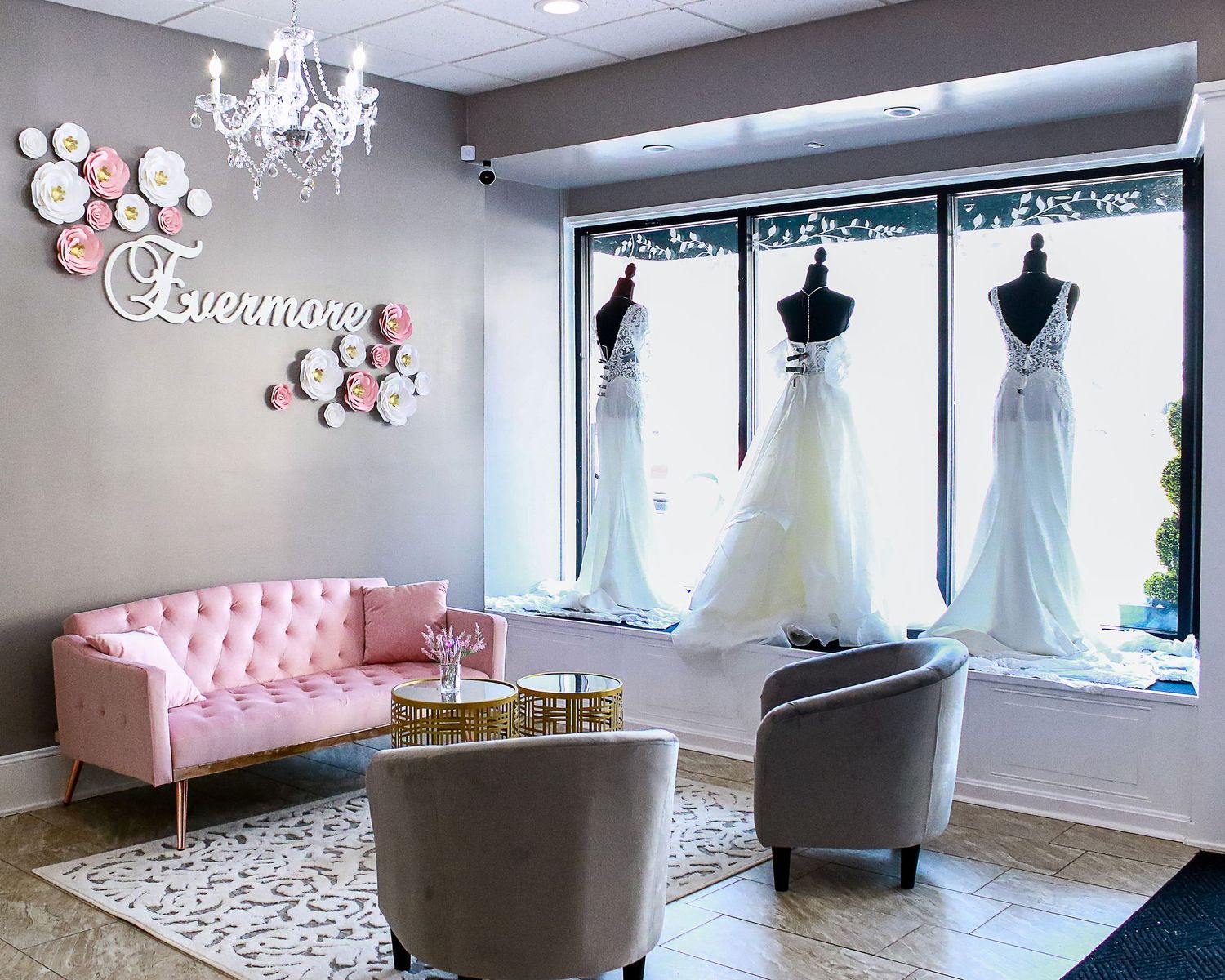 A modern bridal boutique interior with pink furniture and crystal chandeliers.