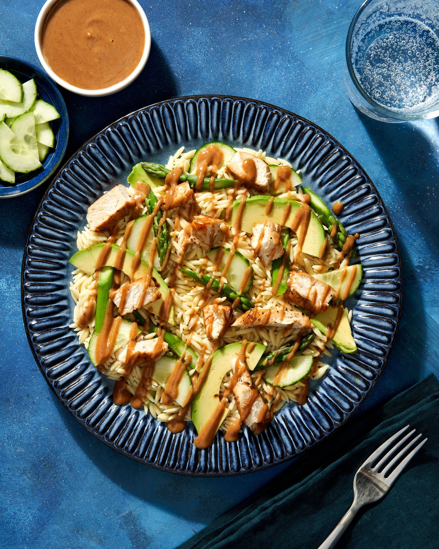 Thai peanut noodle salad with cucumbers and carrots served on dark plates against blue background.