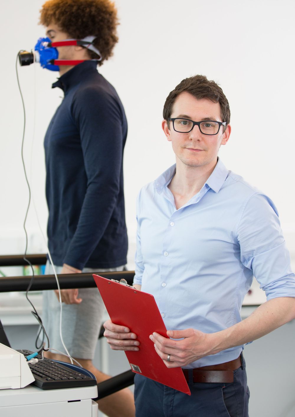 Office setting with two people, one reviewing documents while another uses VR equipment.