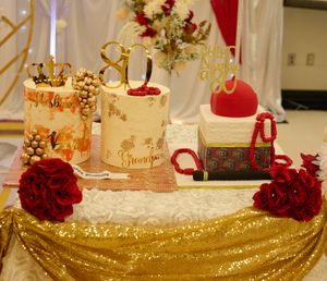 Luxury dessert table with gold crown decorations and red roses on a sparkly gold tablecloth.