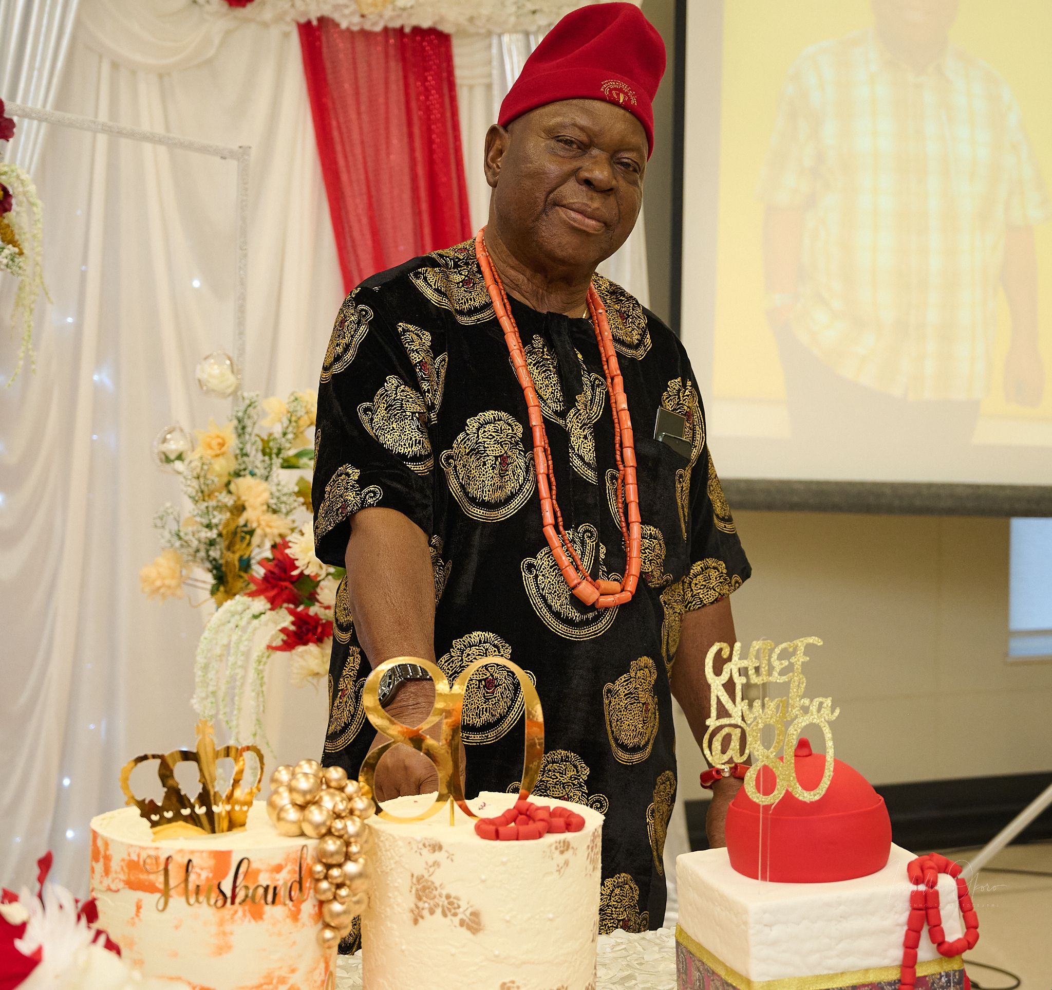 Traditional celebration with decorated cakes and person in ceremonial Nigerian attire.