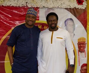 Two men in traditional African attire posing in front of a decorative backdrop.
