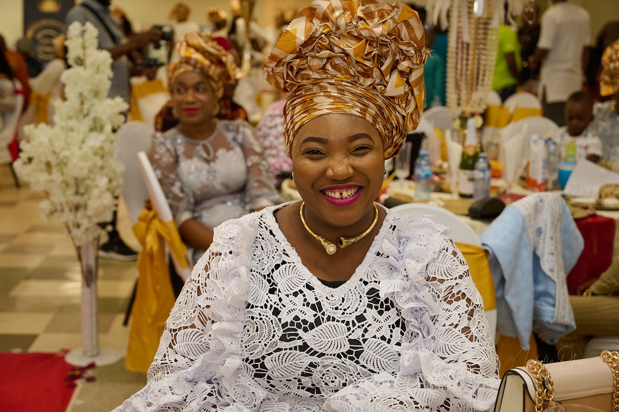Traditional Nigerian celebration with guest wearing white lace and elaborate gele headpiece.