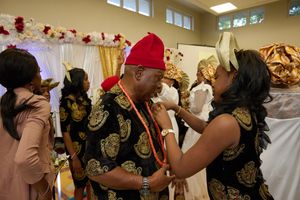 Guests in traditional Nigerian attire celebrating at an indoor event.