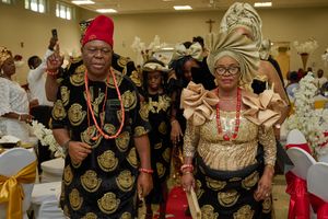 Couple in traditional Nigerian attire with matching gold patterns at formal event.