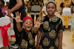 Two young attendees in matching patterned outfits showing excitement at a cultural celebration.