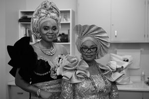 Black and white photo showing two guests in traditional African attire and headwraps at a celebration.