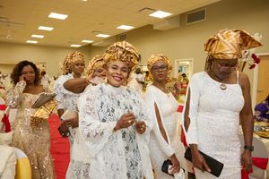 Group celebrating in white and gold traditional attire with ornate headwraps at a festive gathering.