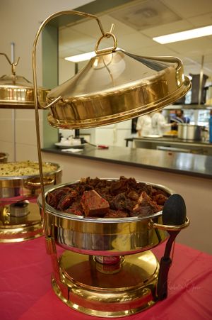 Gold chafing dish filled with meat dishes at an elegant buffet setup.
