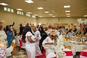 A lively celebration in a banquet hall with guests dancing and mingling around decorated tables.