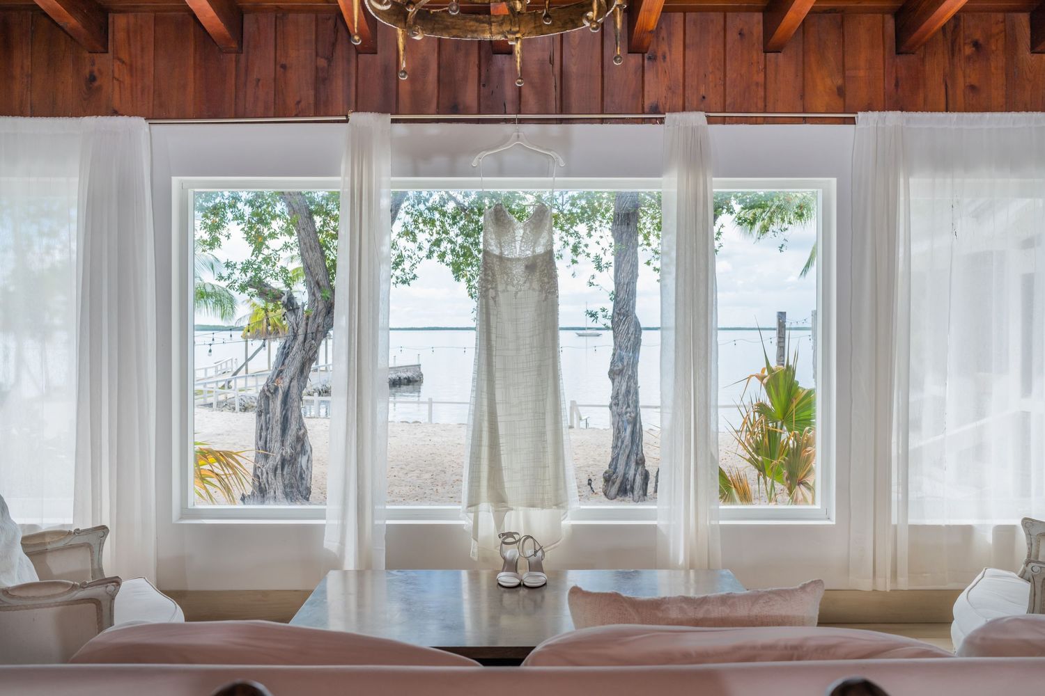 Modern coastal dining room with large windows, white curtains, and natural light streaming in.