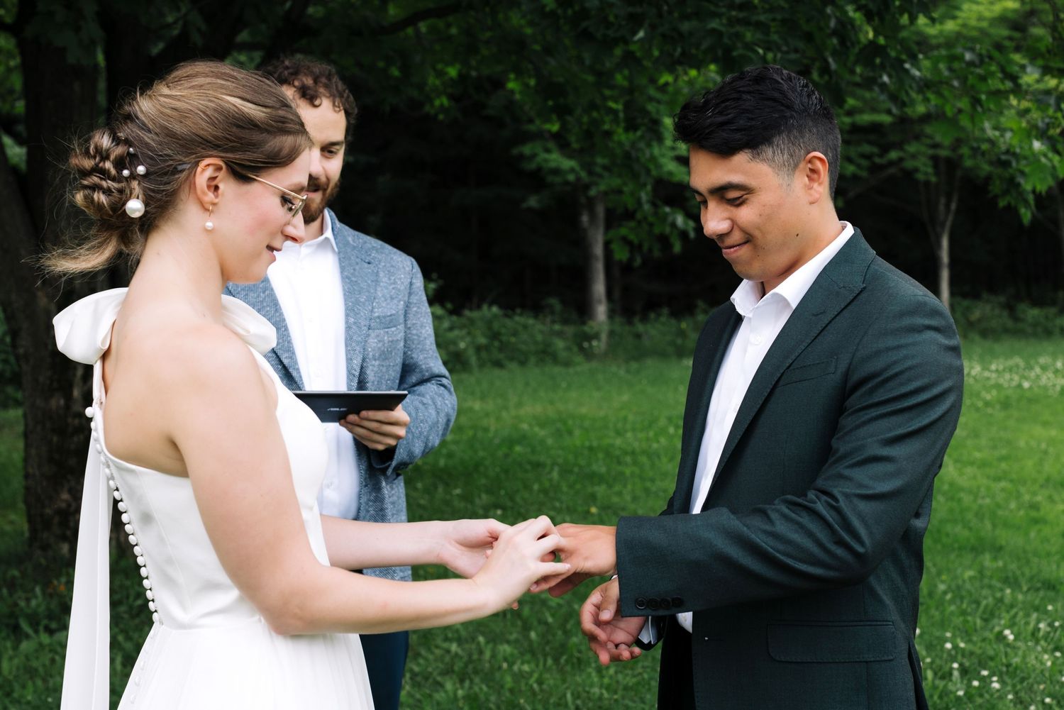 A wedding ceremony takes place in a lush green outdoor garden setting.