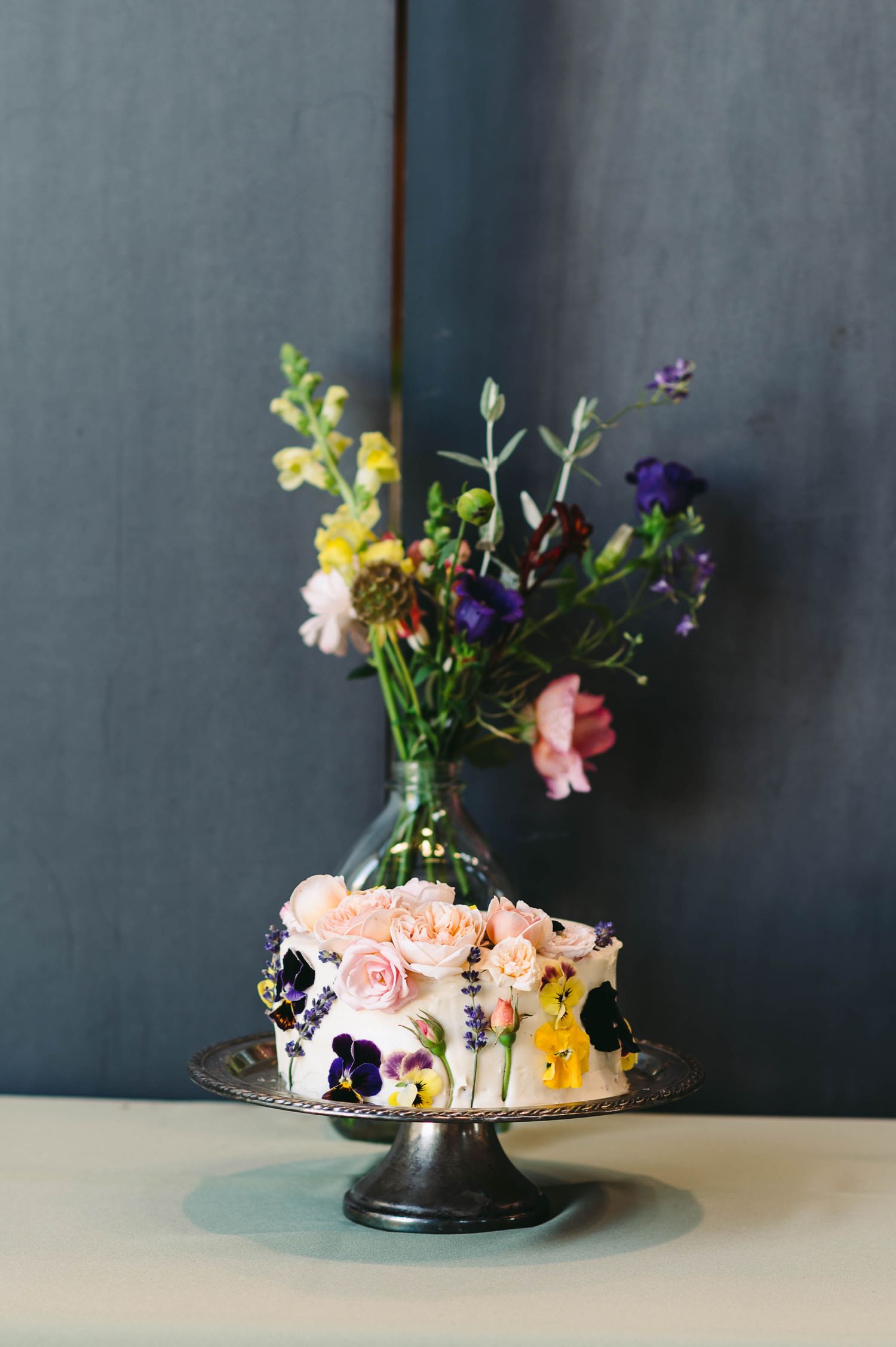 Wedding cake decorated with real flower in purples, yellows, and pinks.