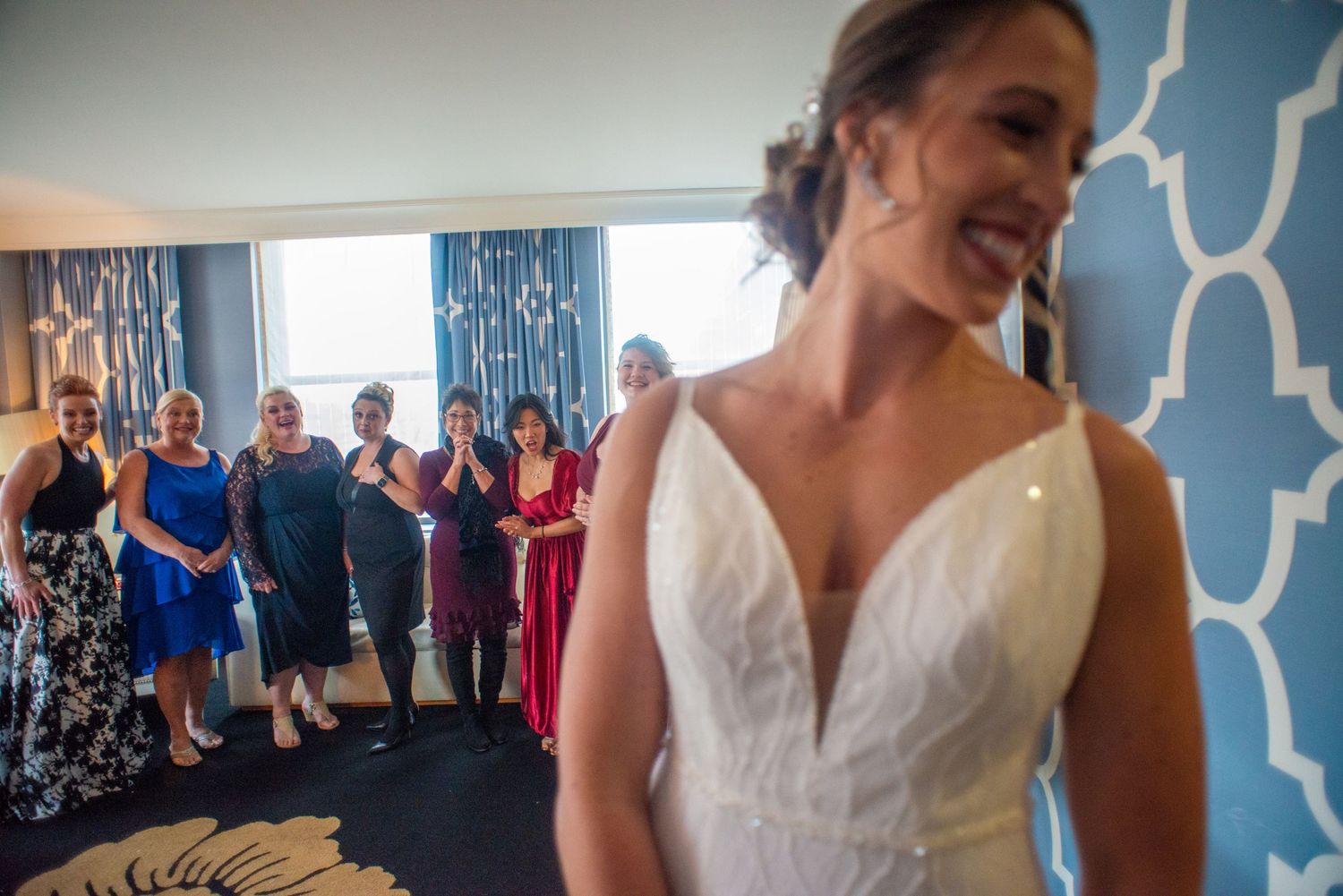 Bride in classic white gown with gathered wedding guests in background.