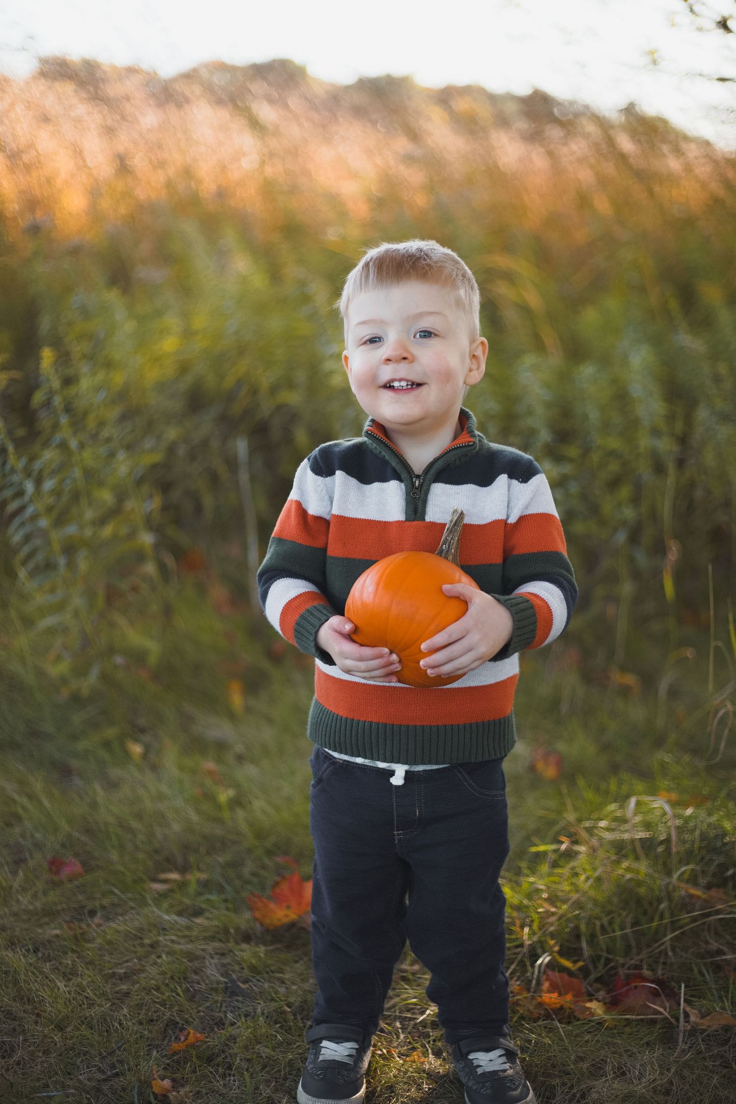 happy smiling toddler holding pumpkin wearing stripes
