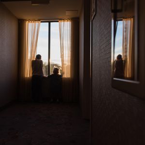 Silhouettes of people looking out a window at sunset.