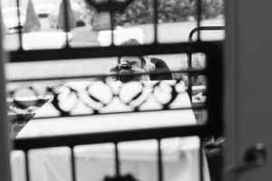 Blurred black and white photo taken through window blinds showing a distant scene.