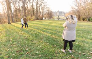 Photographer capturing a scene in a grassy field during golden hour.