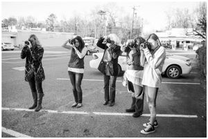 A group of people stand in a line in a parking lot on a winter day.
