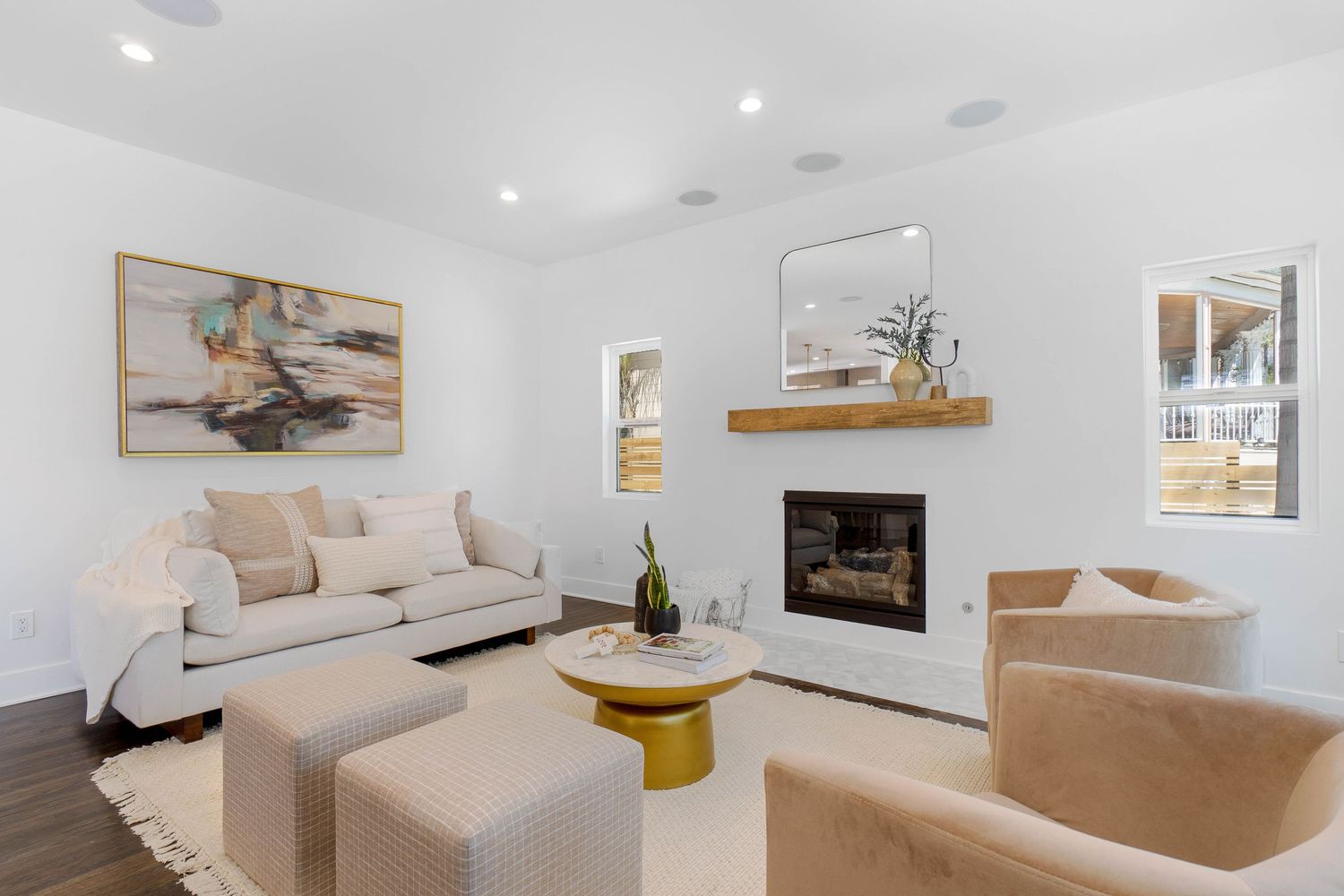 Contemporary white living room with built-in fireplace, floating shelf, and neutral furniture in bright natural light.