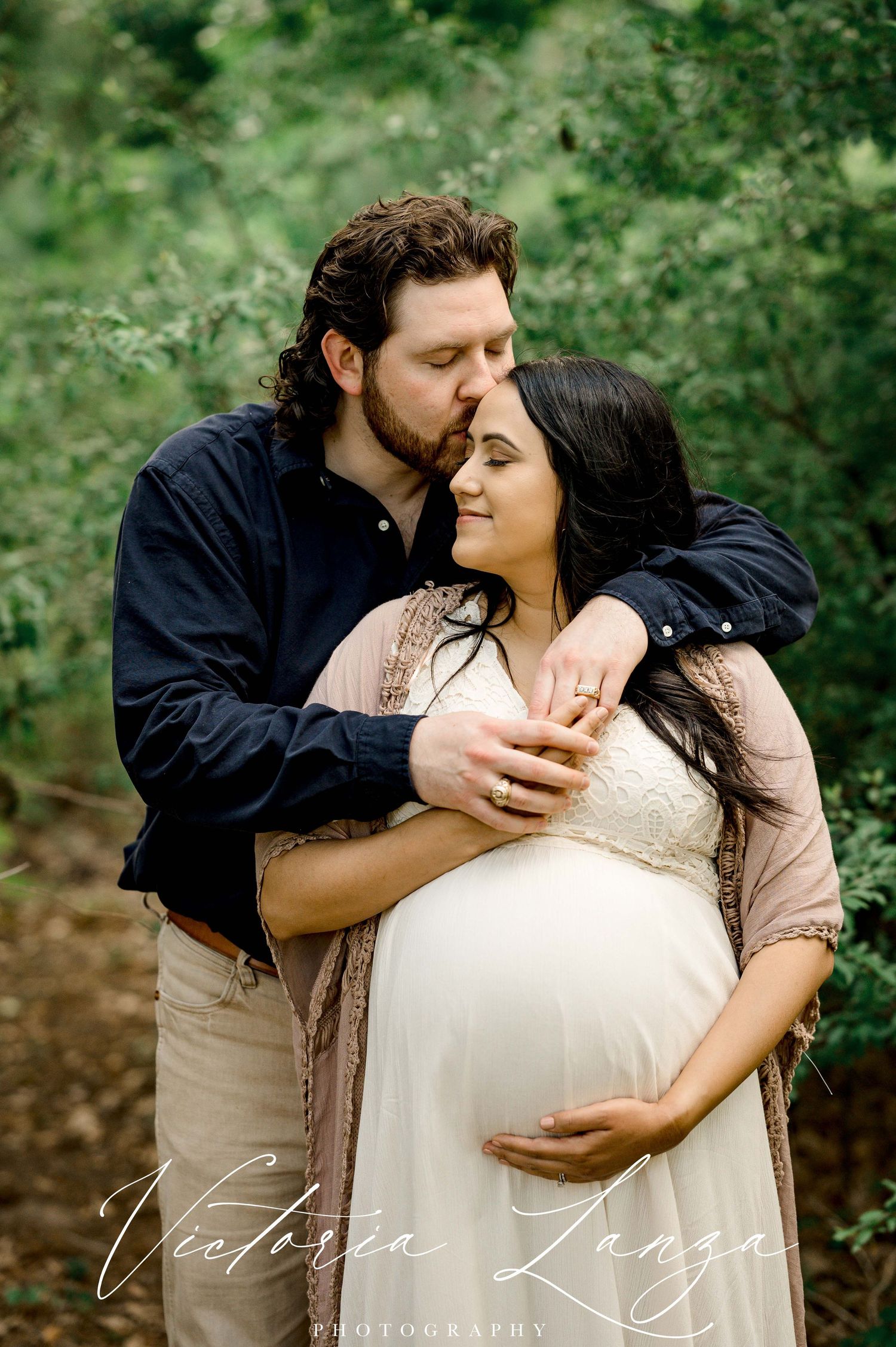 outdoor natural light maternity photo with husband kissing wife on forehead  at memorial park in houston