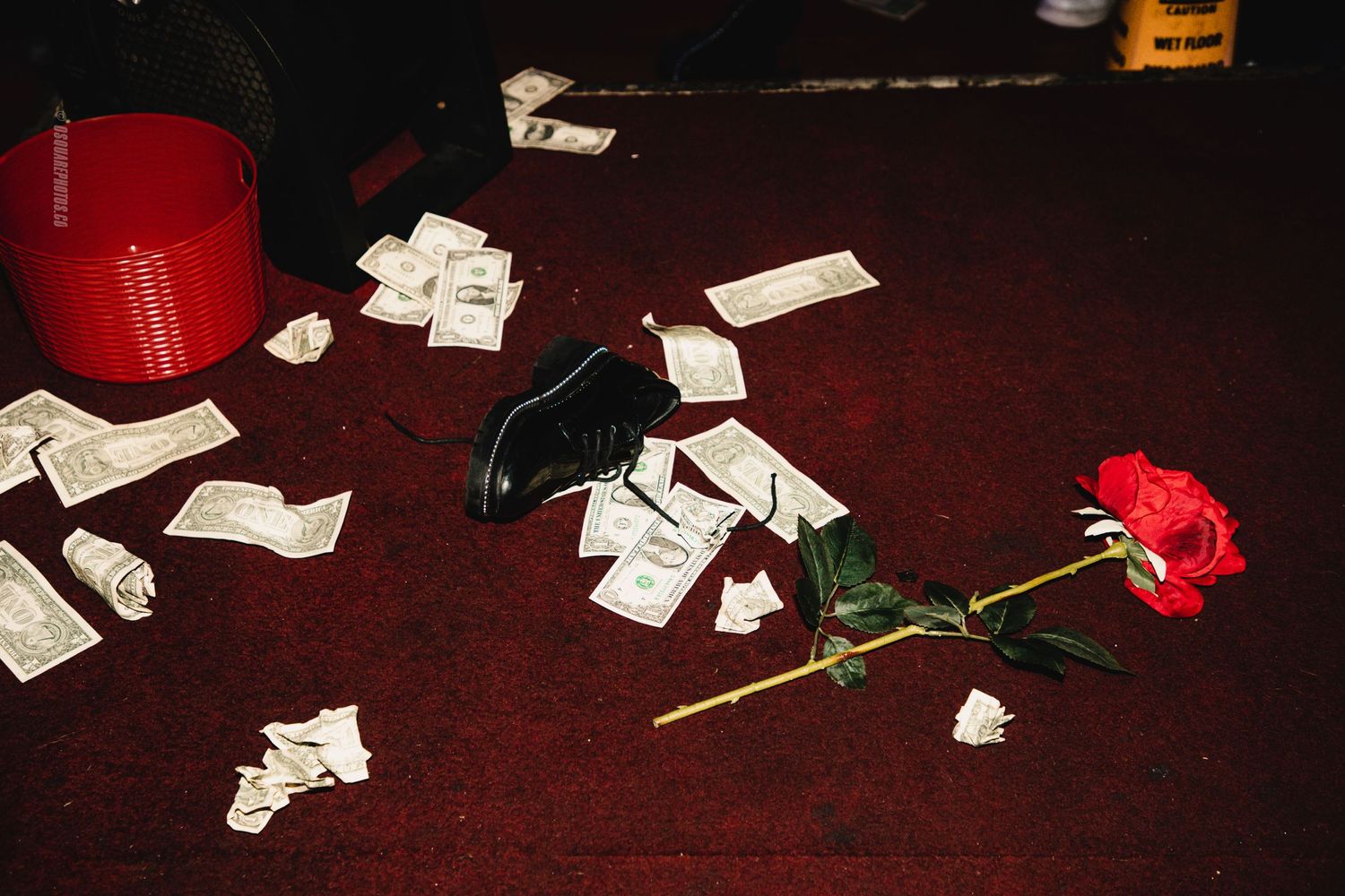A single red rose and scattered papers on a dark wooden table with dramatic lighting.