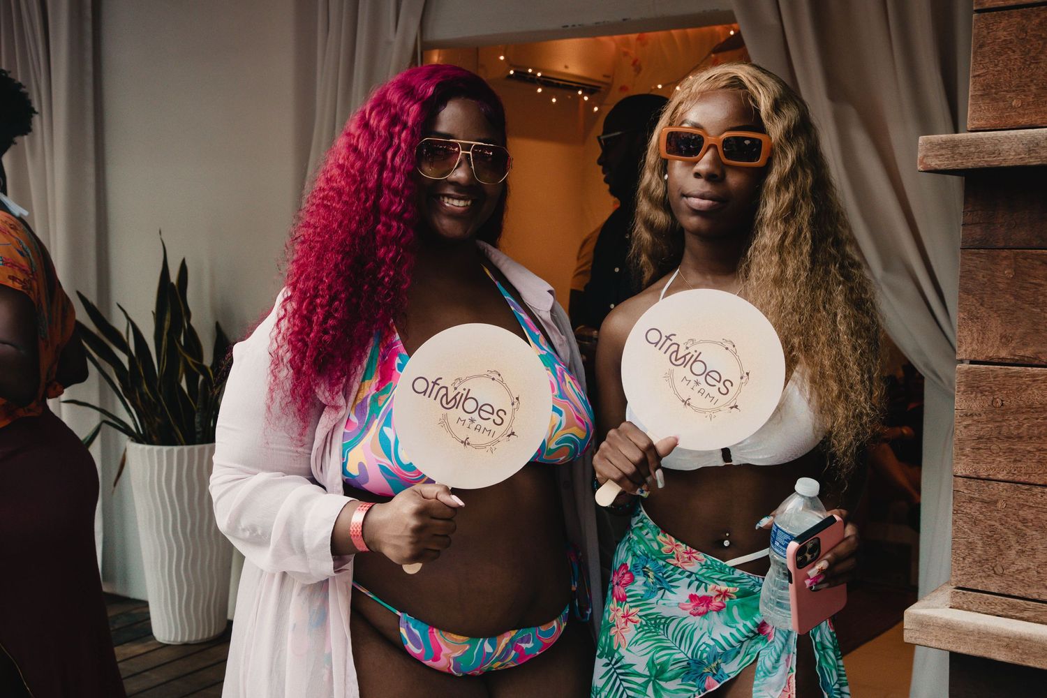 Two people holding branded plates at a party with decorative lighting.