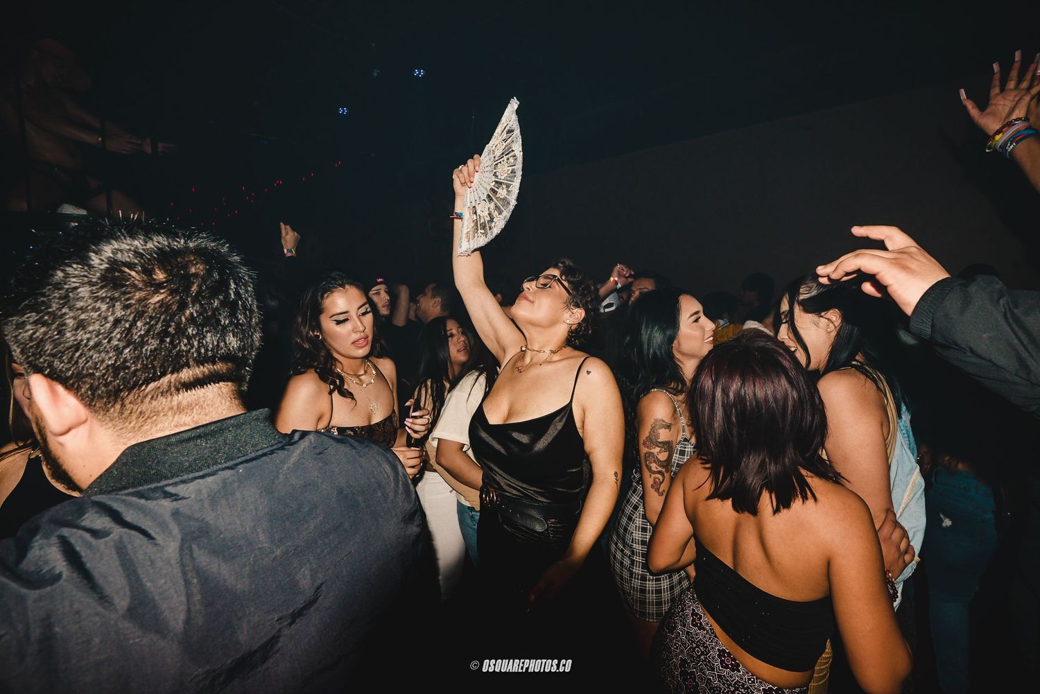 A crowded nightclub dance floor filled with people having fun under dim lighting.