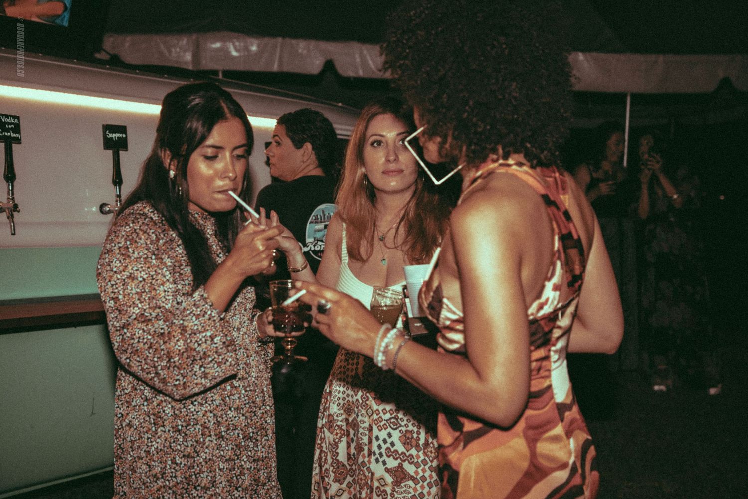 Three people enjoying drinks together at a dimly lit party venue.
