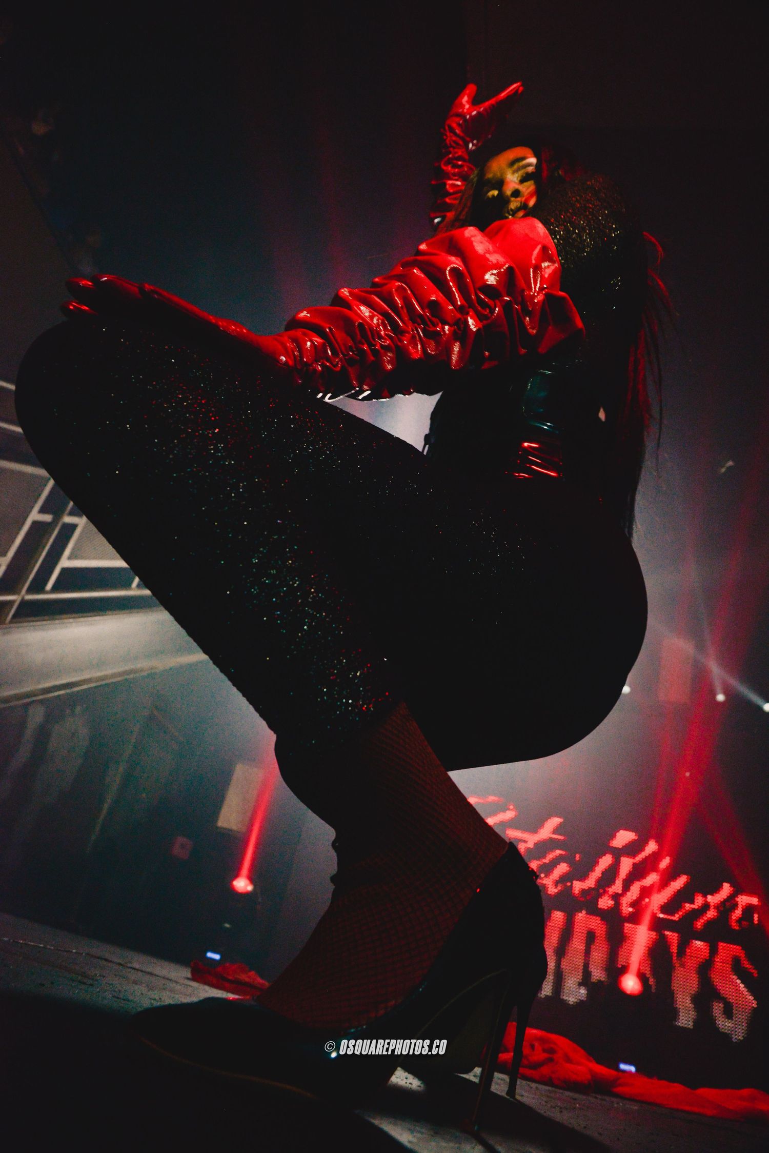 Performer in red lighting jumping during an energetic stage performance.