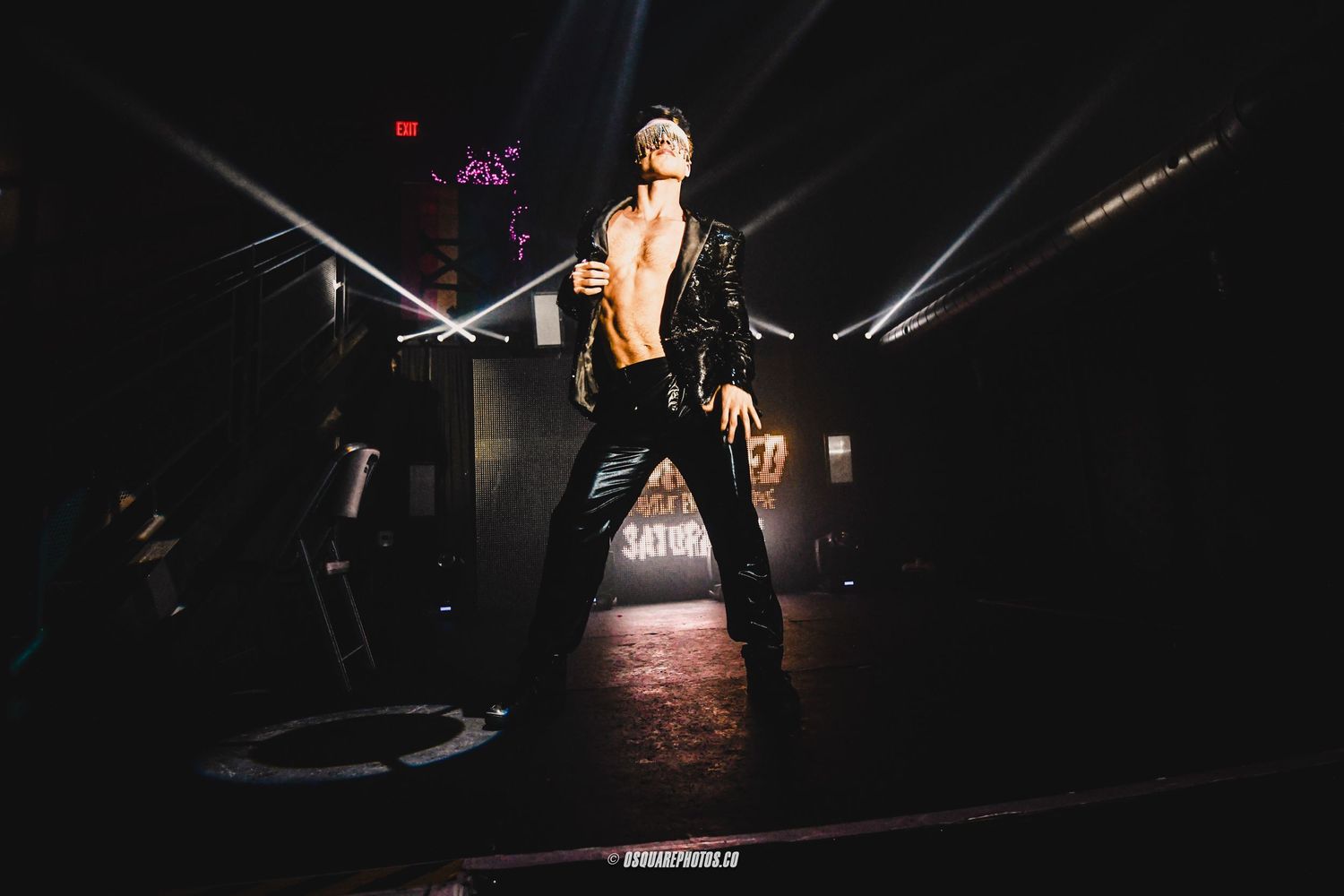 Performer on dark stage with dramatic lighting and spotlight effects.