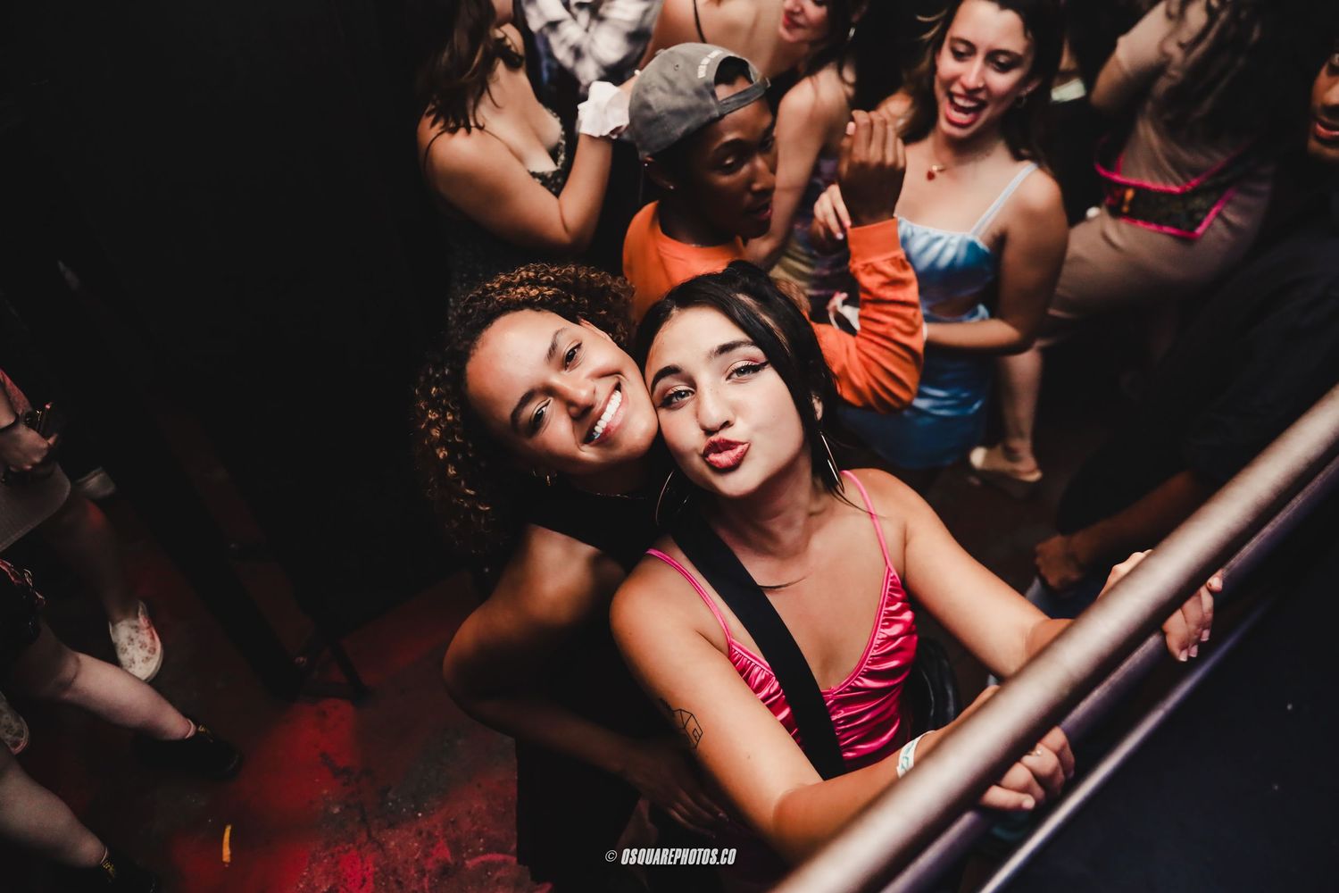 Party-goers having fun and posing for photos in a dimly lit nightclub atmosphere.