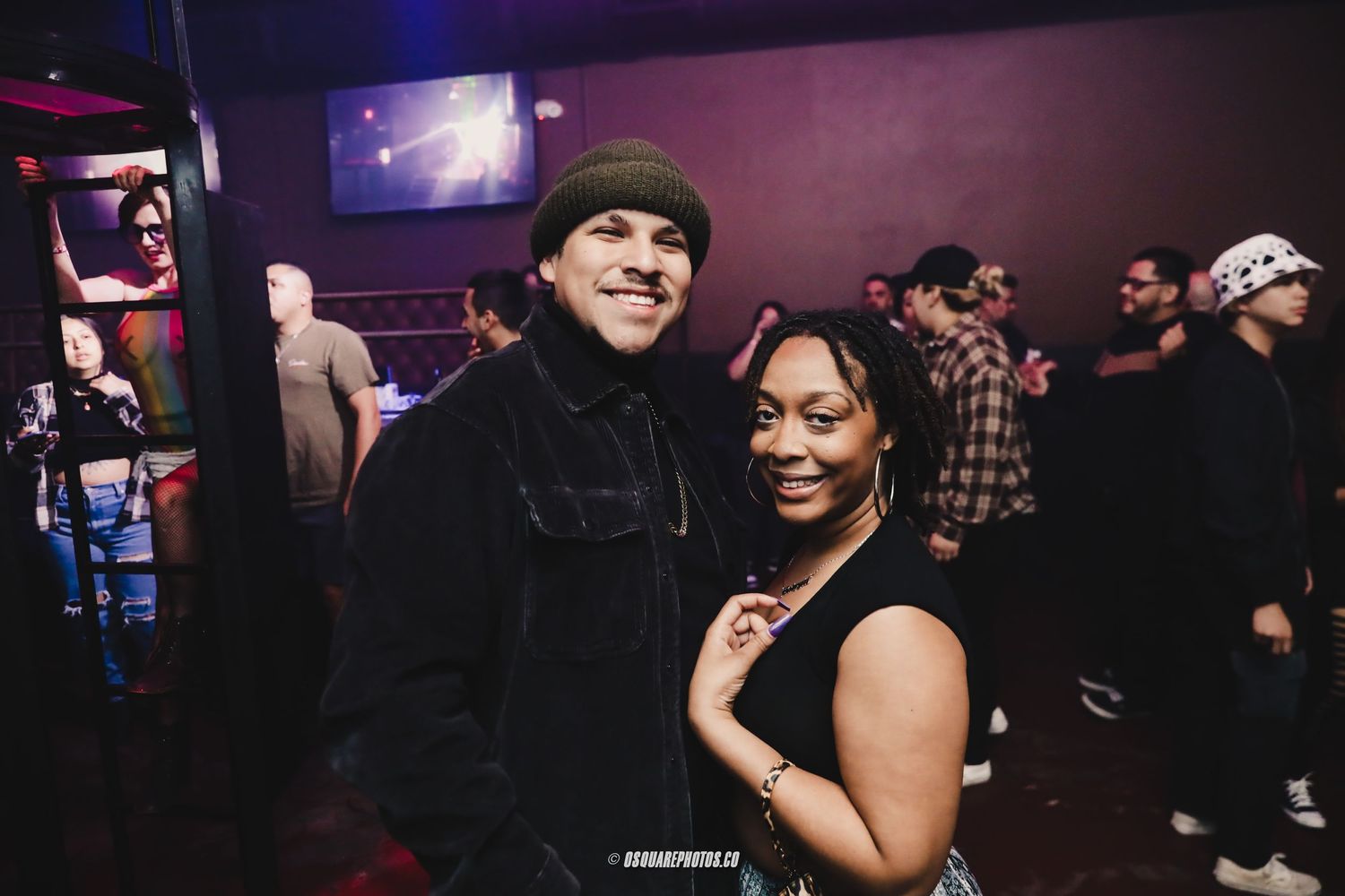 Nightclub attendees sharing a friendly moment together against dark club background.