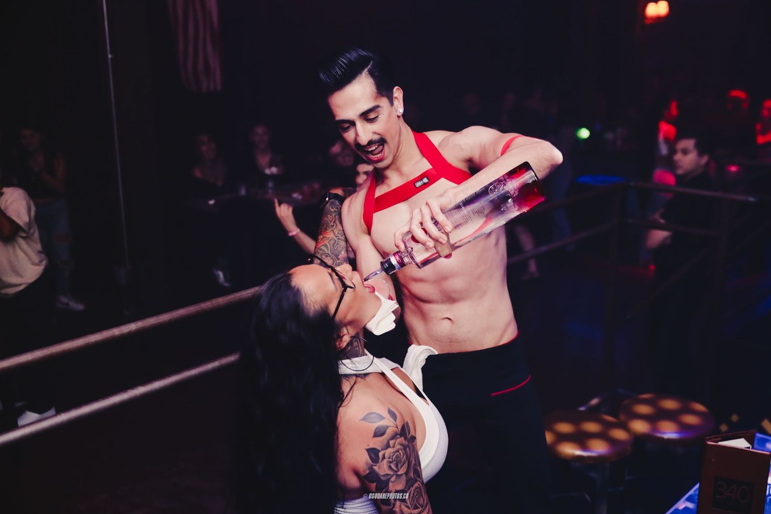 Shirtless performer in red suspenders dancing energetically during club entertainment show.