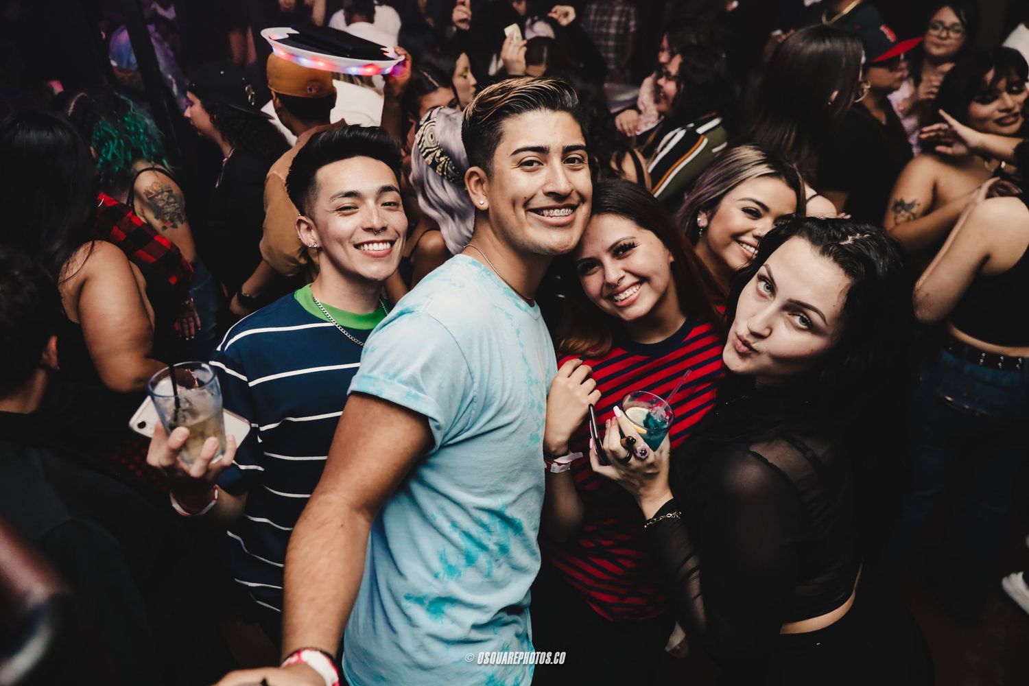 Young friends enjoying a lively night out at a crowded club, smiling and posing together.